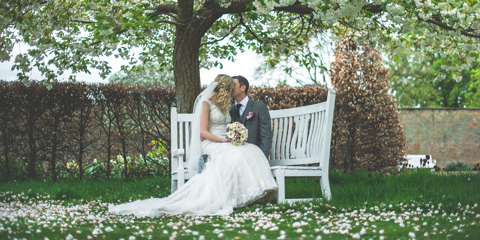 The newlyweds sit on a white bench in the Walled Garden at this stunning Shropshire wedding venue
