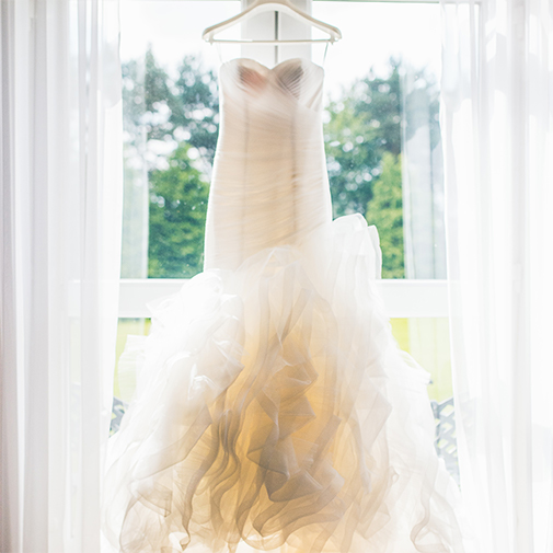The bride’s wedding dress hangs in front of a window – wedding dresses
