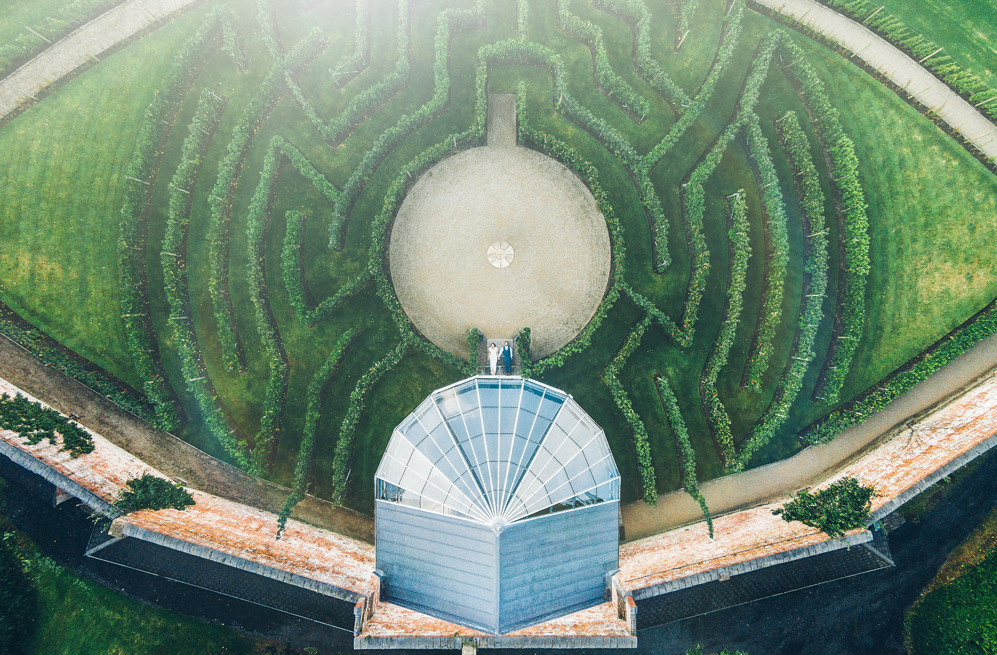 A bride and groom lay in the middle of the fruit tree maze for a fantastic aerial wedding photo