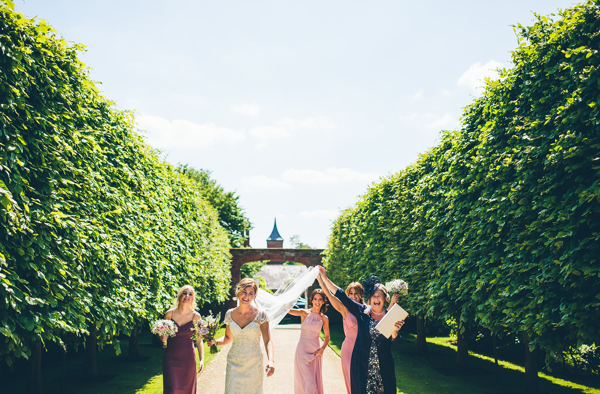 The bride and her bridal party make their way to the wedding ceremony in the Glasshouse at this Cheshire wedding venue