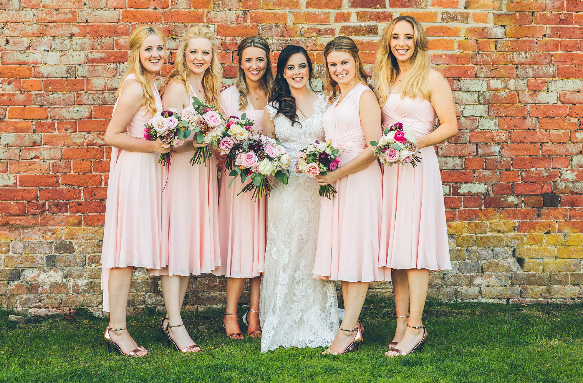 Bridesmaids look stunning in knee-length pastel pink bridesmaids dresses as they join the bride at Combermere Abbey