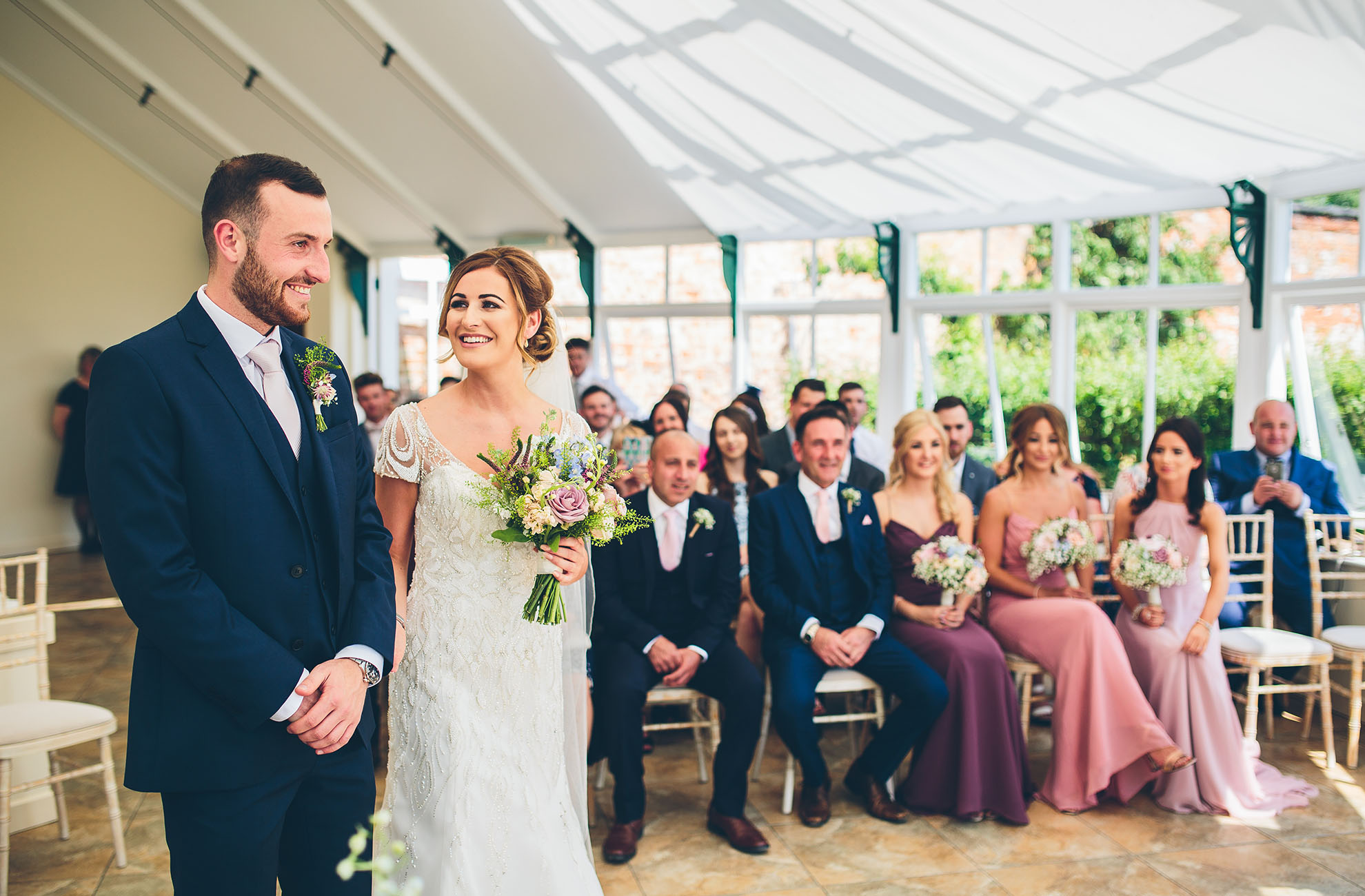The bride and groom enjoy their wedding ceremony in the Glasshouse at Combermere Abbey