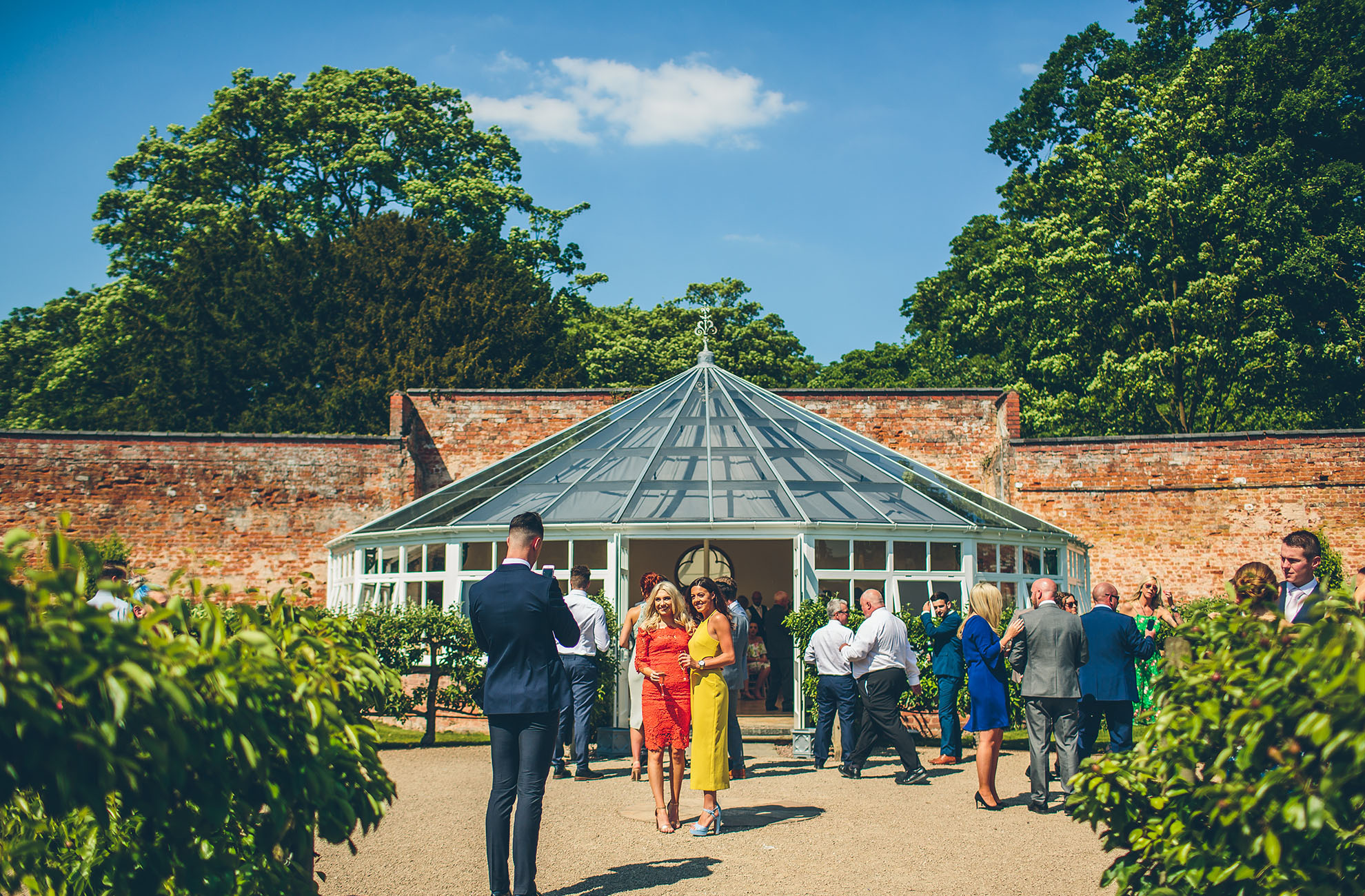 At this Cheshire wedding venue guests enjoy a drinks reception outside the Glasshouse