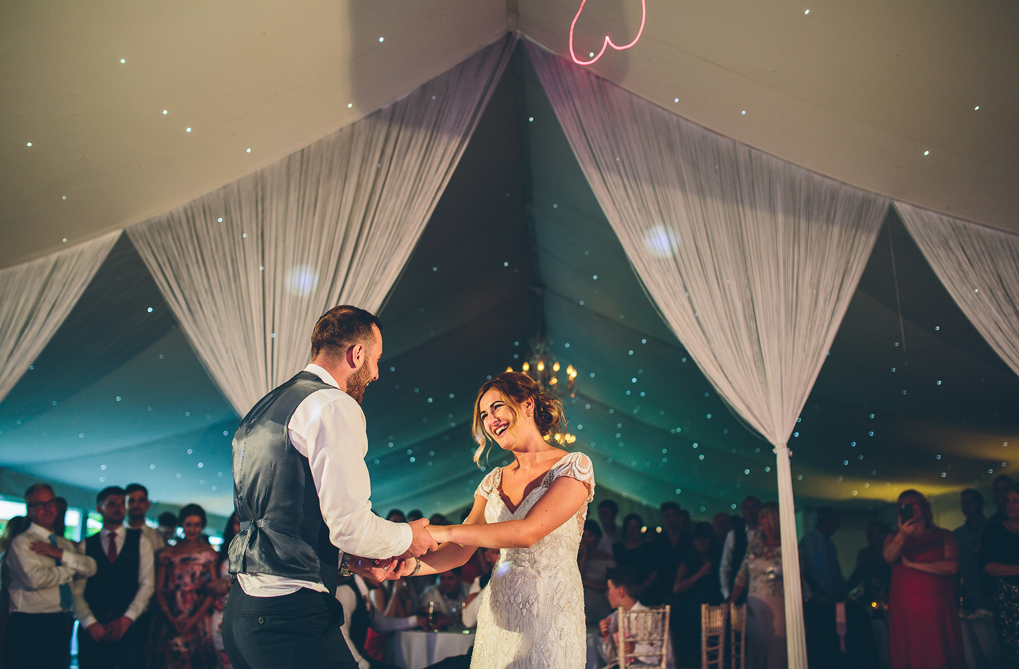 A bride and groom perform their first dance in front of guests in the Pavillion at Combermere Abbey